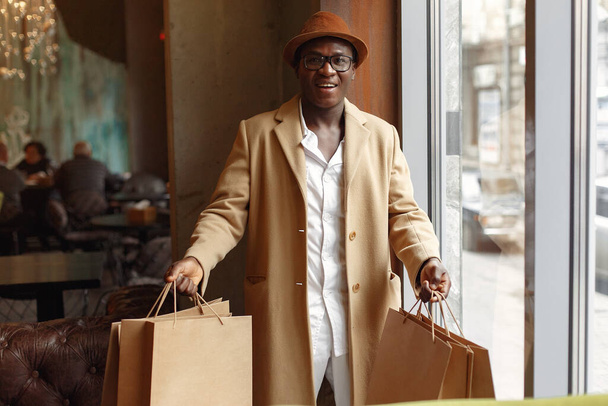 Black man standing in a cafe with shopping bags - Photo, Image