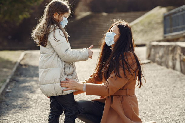 Mother with daughter walks outside in masks - 写真・画像