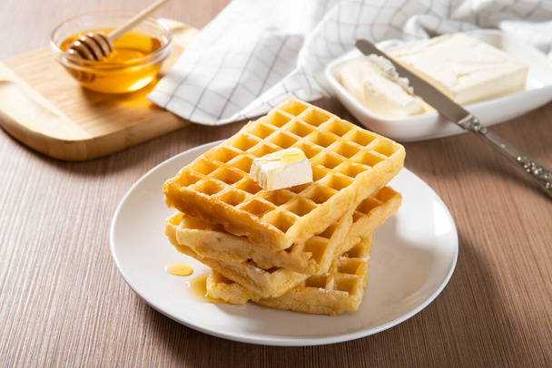 Plato con deliciosos gofres con miel y una rebanada de mantequilla. Primer plano
 - Foto, imagen