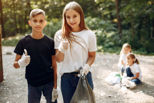 Children collects garbage in garbage bags in park - Fotó, kép