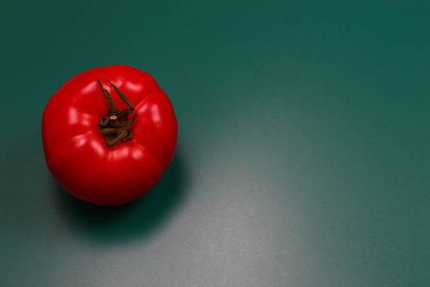 Red tomato on the background of the cutting Board color dark aquamarine with space for writing and text - Fotó, kép