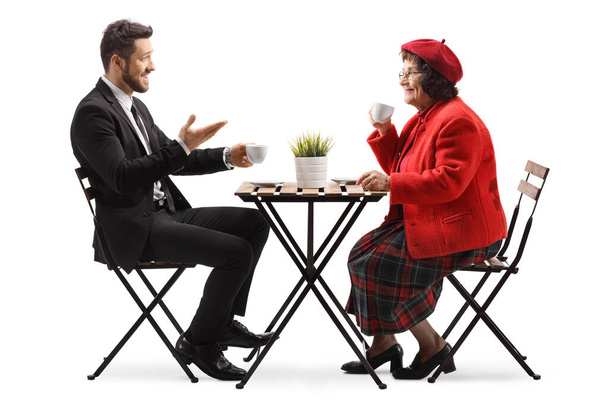Young man in a suit sitting in a cafe with an elderly woman and talking isolated on white background - Zdjęcie, obraz