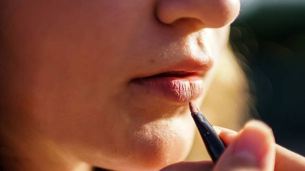 若い女性は赤い鉛筆で唇を描く。クローズアップショット - 写真・画像