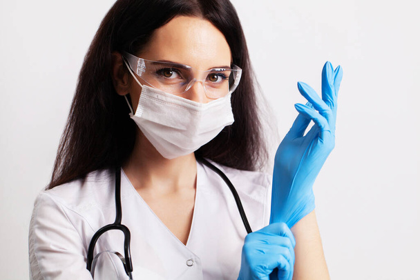 Portrait of a doctor in glasses and a white medical gown wearing personal protective equipment - Foto, Imagem