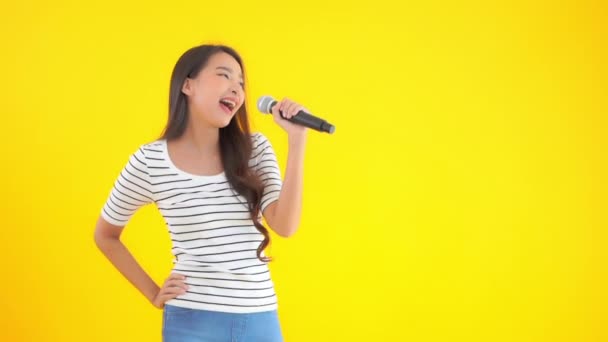 Sarıda mikrofonla şarkı söyleyen Asyalı güzel bir kadının görüntüleri. - Video, Çekim