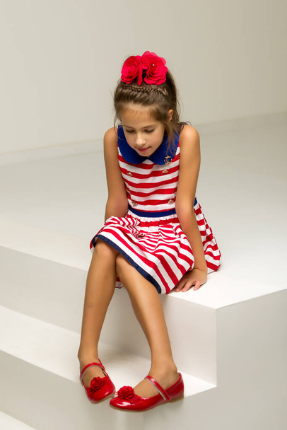 Beautiful little girl is sitting on the white staircase. - Foto, imagen