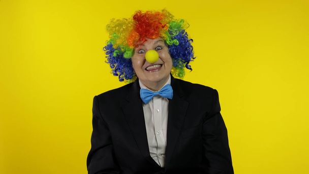 Senioren-Clown mit bunter Perücke lächelt, macht alberne Gesichter, albert herum - Foto, Bild