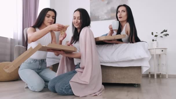 The pretty ladies are eating a takeaway pizza in bedroom and smiling - Video