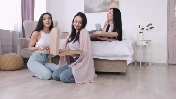 The pretty ladies are eating a takeaway pizza in bedroom and smiling - Video