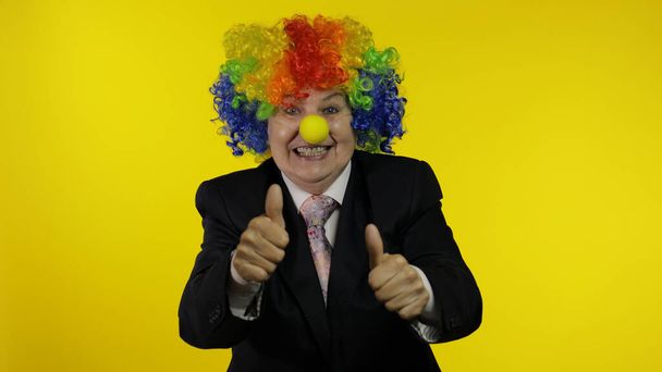 Пожилая клоун босс бизнесвумен в парике показывает большие пальцы вверх. Хэллоуин
 - Фото, изображение