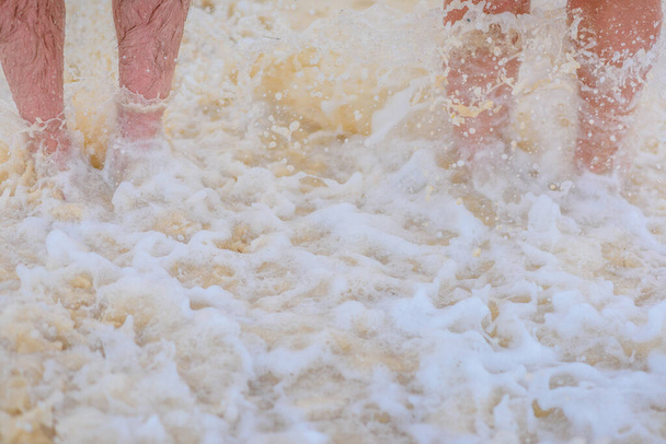 Две пары ног на белом песке с волной
 - Фото, изображение