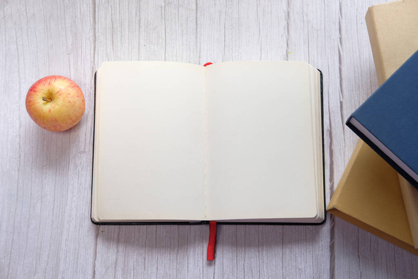 apple , open diary, books and stationary on wooden background  - Photo, Image