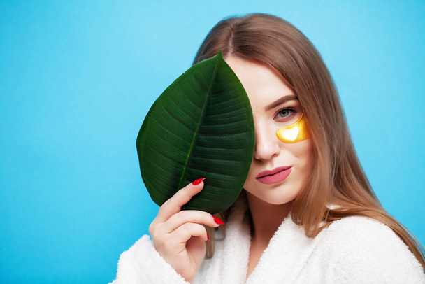 Face care, young woman holding a green leaf near facial skin health - Fotografie, Obrázek