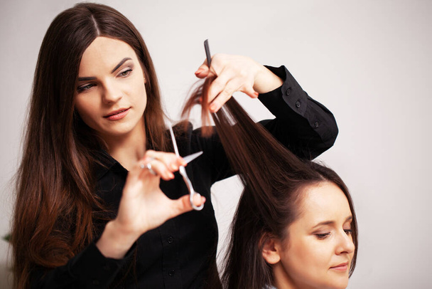 Professionelle Stylistin macht aus einer jungen Frau eine schöne Frisur - Foto, Bild