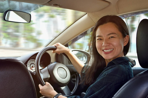 車を運転する若い女性の笑顔. - 写真・画像