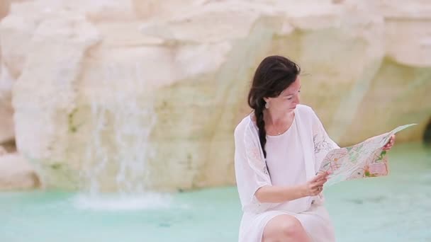 美しい女性トレビの泉、ローマ、イタリアの近くの観光都市マップを見て。幸せな女の子はヨーロッパでイタリアの休暇を楽しむ. - 映像、動画