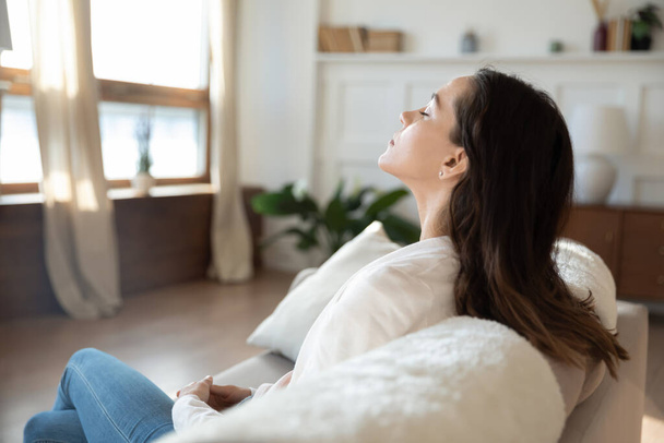 Calm young woman relax on sofa breathing fresh air - Foto, imagen
