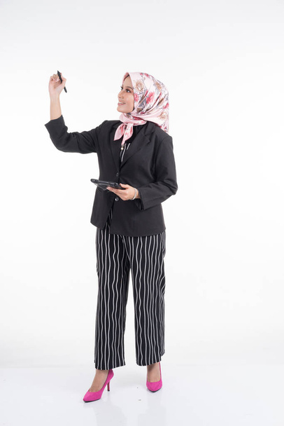 ビジネスの衣装を着た美しいイスラム教徒の女性の完全な長さの肖像画と白の背景に隔離された混合ポーズやジェスチャーでヒジャーブ。テクノロジー、ビジネス、財務のテーマに適しています. - 写真・画像