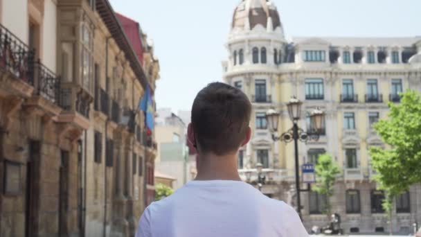 mladý turista v lékařské ochranné černé masce navštíví památky na výlet do Evropy a Španělska. Cestovní koncept po epidemii koronaviru. Otevírání hranic a začátek turistické sezóny - Záběry, video
