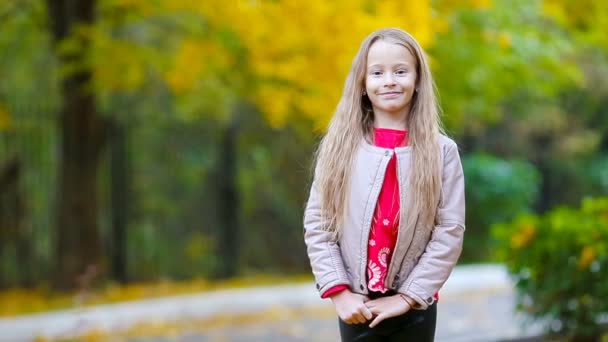 Portrait of adorable little girl in fall looking at camera and smiling - Footage, Video