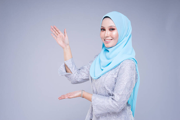 Hermosa modelo femenina en varias poses que lleva kebaya moderna y hijab, una ropa de estilo de vida urbano para mujeres musulmanas aisladas sobre fondo gris. Belleza y hijab concepto de moda. Media longitud
. - Foto, imagen