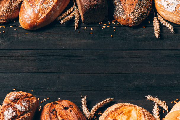 Bread border on wood background with copy space. Different types of bread arranged as frame with spikelets. Bakery, cooking and grocery store concept. - Fotoğraf, Görsel