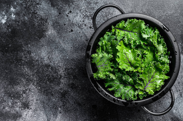 Fresh kale salad in a colander. Vegetarian food. Black background. Top view. Copy space. - Zdjęcie, obraz