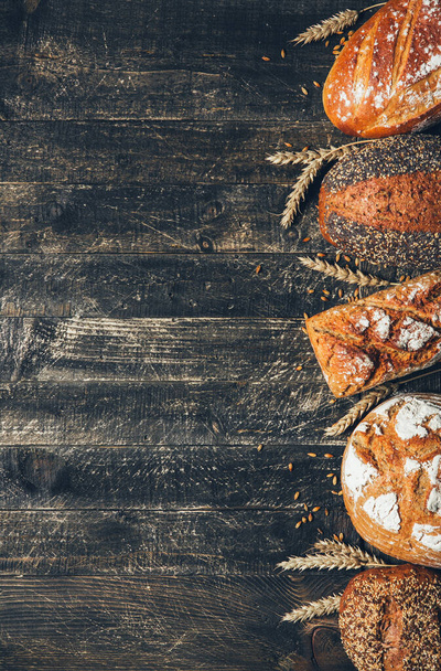 Bread border on wood background with copy space. Whole grain loaves with spikelets. Different types of bread. Bakery, cooking and grocery store concept. - Fotó, kép