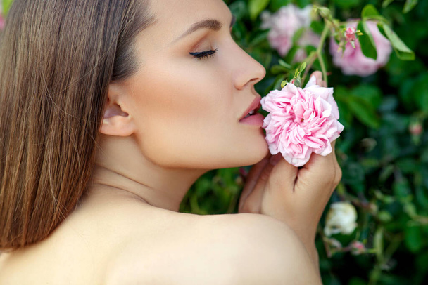 Mooie vrouw in rozen op de natuur. - Foto, afbeelding
