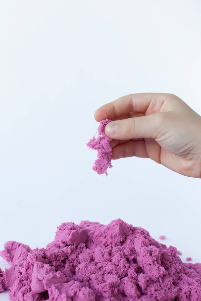 Sabbia cinetica porpora in mano isolata su fondo bianco. Sabbia colorata per modellare per bambini
 - Foto, immagini
