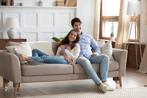 Retrato de pareja sonriente inquilinos relajarse en el sofá
 - Foto, Imagen