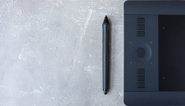 graphic tablet with a pen, for illustrators, designers and retouchers, black on a gray concrete background. - Foto, afbeelding