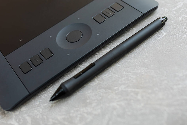 grafische tablet met pen, voor illustratoren, ontwerpers en retouchers, zwart op een grijze betonnen achtergrond. - Foto, afbeelding