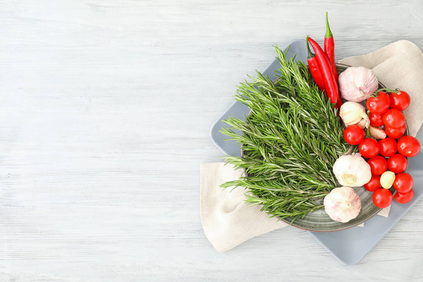 Plate with fresh rosemary and vegetables on wooden background - Φωτογραφία, εικόνα