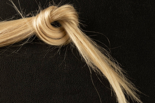 tricoté dans un nœud de cheveux blonds féminins sur un noir
 - Photo, image