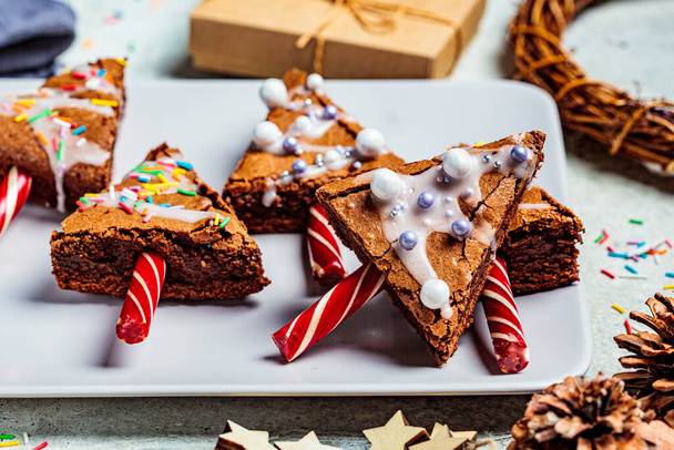 Christmas tree brownies with candy cane and icing, gray background. Christmas food concept. - Fotó, kép