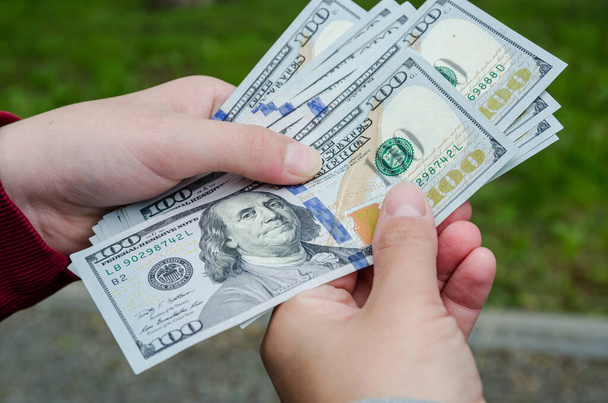 γυναικεία χέρια που δίνουν (ή πληρώνουν) χρήματα σε ένα άτομο, χαρτονομίσματα σε δολάρια - πιστωτικές, δωροδοκίες και οικονομικές έννοιες - Φωτογραφία, εικόνα