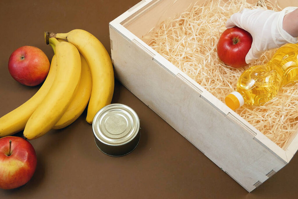 Donation food concept, wooden box with products, free delivery concept, fruits, oil in bottle and canned food, food drive  - Fotografie, Obrázek