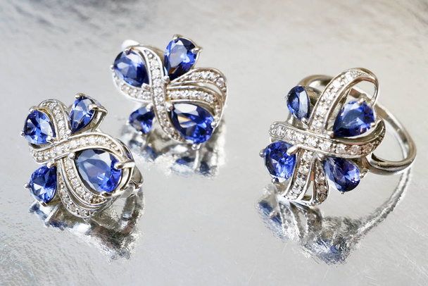 conjunto de joyas con anillo y pendientes sobre fondo plateado, concepto de tienda de empeño, concepto de joyería - Foto, imagen