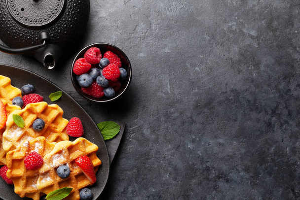 Вкусные бельгийские вафли с мороженым и летними ягодами и чай на завтрак. Вид сверху с пространством для копирования - Фото, изображение
