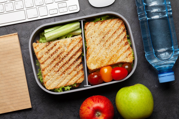 Gezonde lunchbox met broodjes en groenten op kantoortafel. Bovenaanzicht. Vlakke plaat - Foto, afbeelding