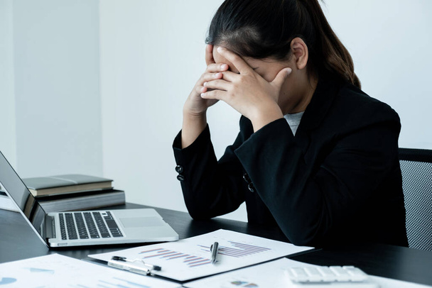 Уставшая деловая женщина со стрессовой головной болью от работы сидит за рабочим столом
. - Фото, изображение
