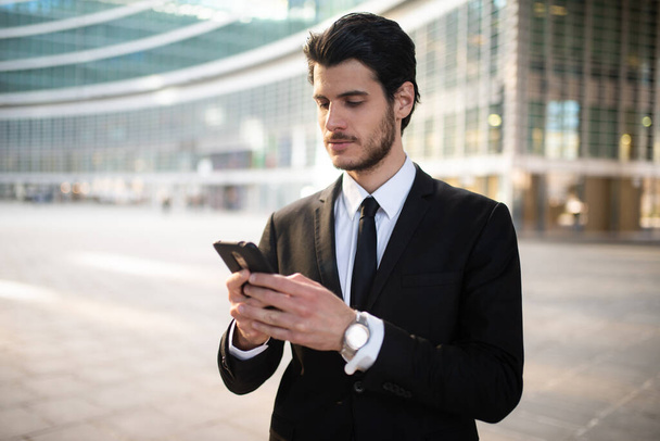 Businessman using an app on his smartphone in a business environment - Foto, Imagen