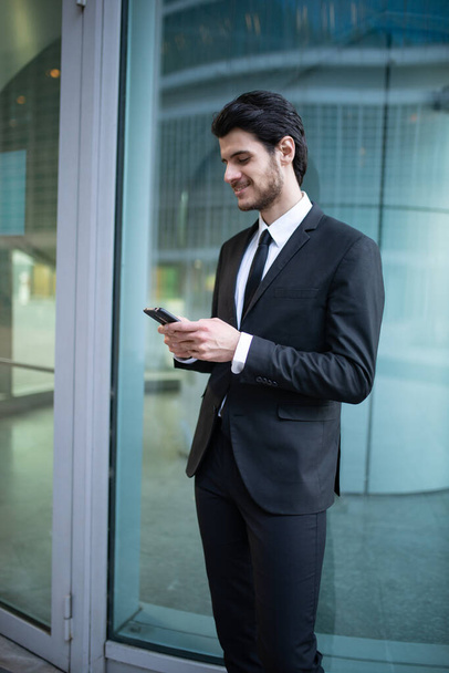 Businessman using an app on his smartphone in a business environment - Fotoğraf, Görsel