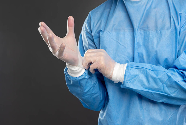 Crop doctor putting on medical gloves in studio - Zdjęcie, obraz