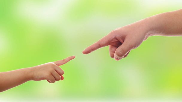 Small child's hand reaches fathers hand man over blurred green background, parenting love concept - Photo, Image