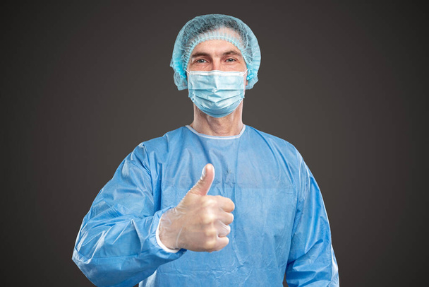Cheerful male doctor showing thumb up in studio - Photo, image