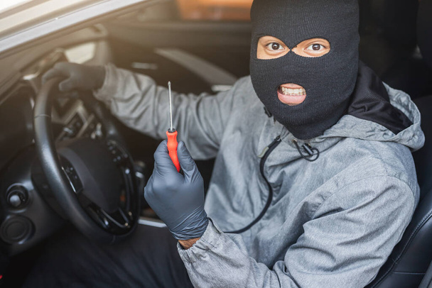 El ladrón usa un destornillador robando un coche. El concepto de seguro de vehículos
. - Foto, imagen