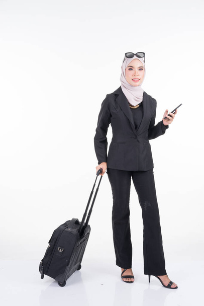 Muslim businesswoman on a business trip, with luggage isolated on white background. Suitable for cut out, manipulation or composite works for travel or business concept. Full length portrait. - Фото, изображение