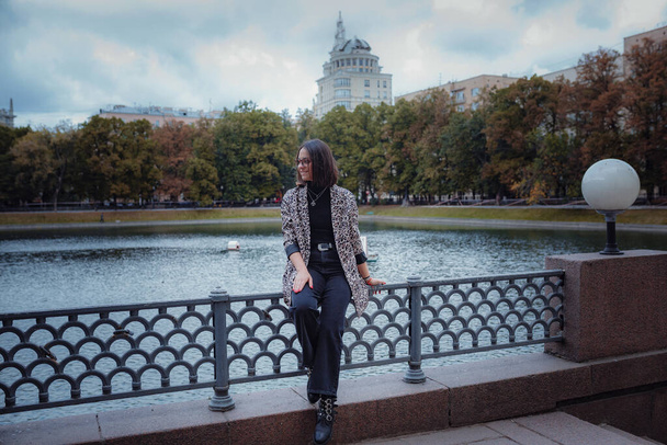 Schöne junge brünette Frau geht in Moskau. In einer trendigen Leopardenjacke. Lächeln und durch die Stadt spazieren. Einkaufen gehen. - Foto, Bild